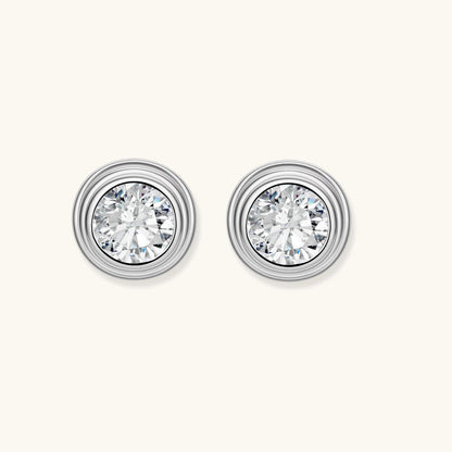 Close-up of sterling silver stud earrings featuring concentric circular frames with brilliant moissanite centers